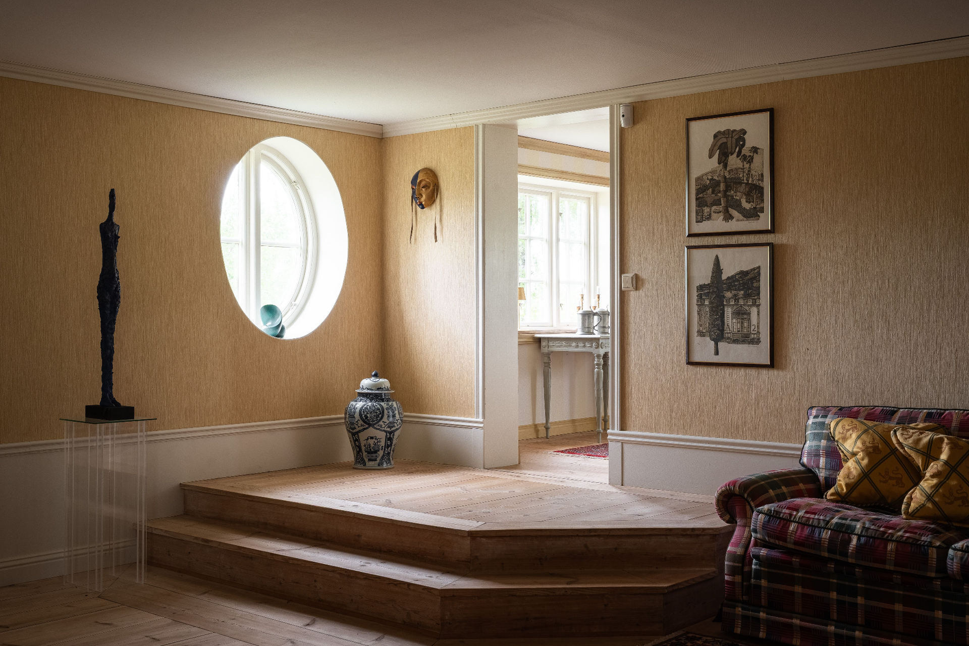 Klassiskt inrett rum med ovalt fönster och konst, bostadsfoto Småland.