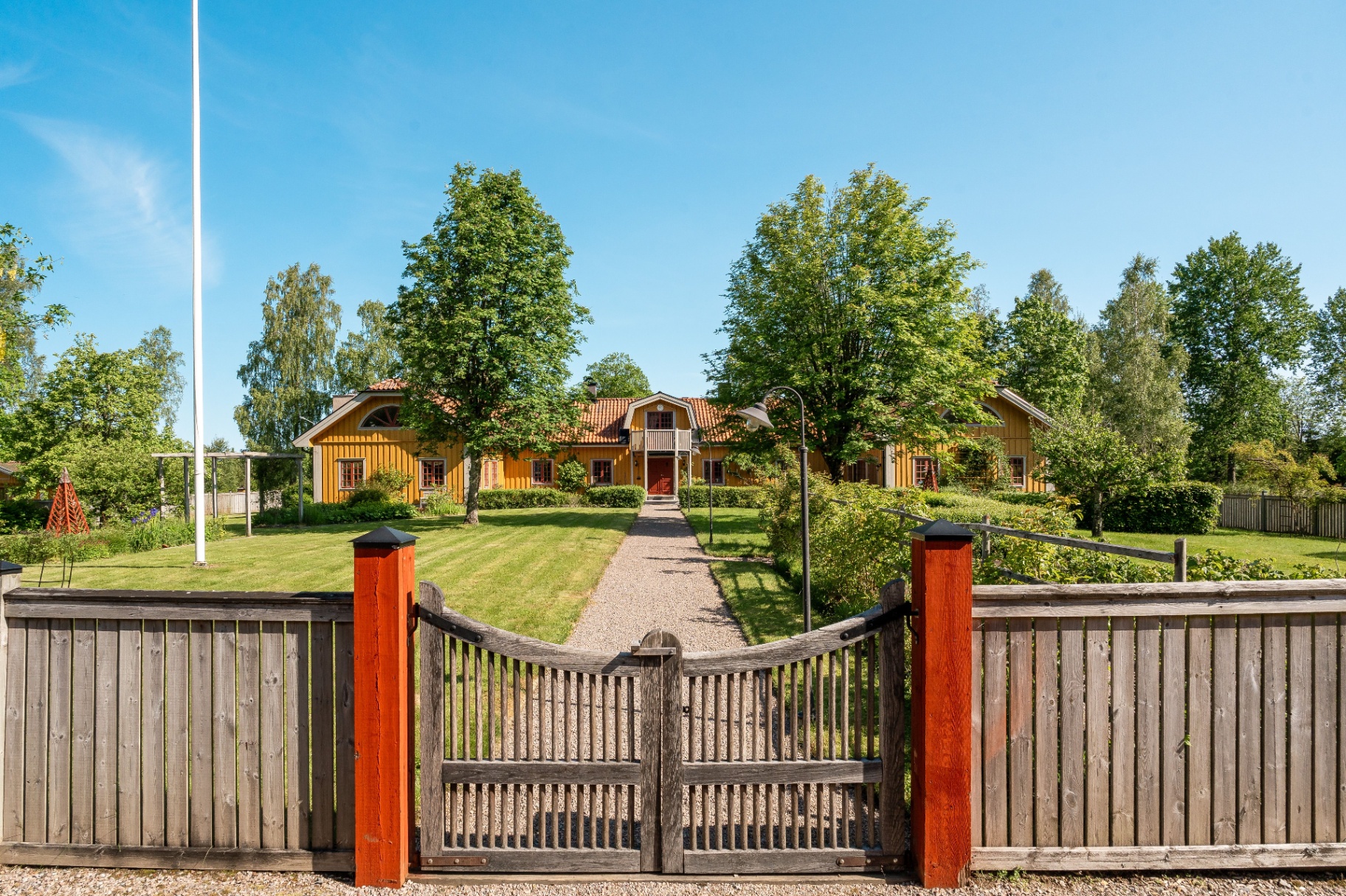 Gul mangårdsbyggnad med trädgård och grind, exteriörfoto Småland.