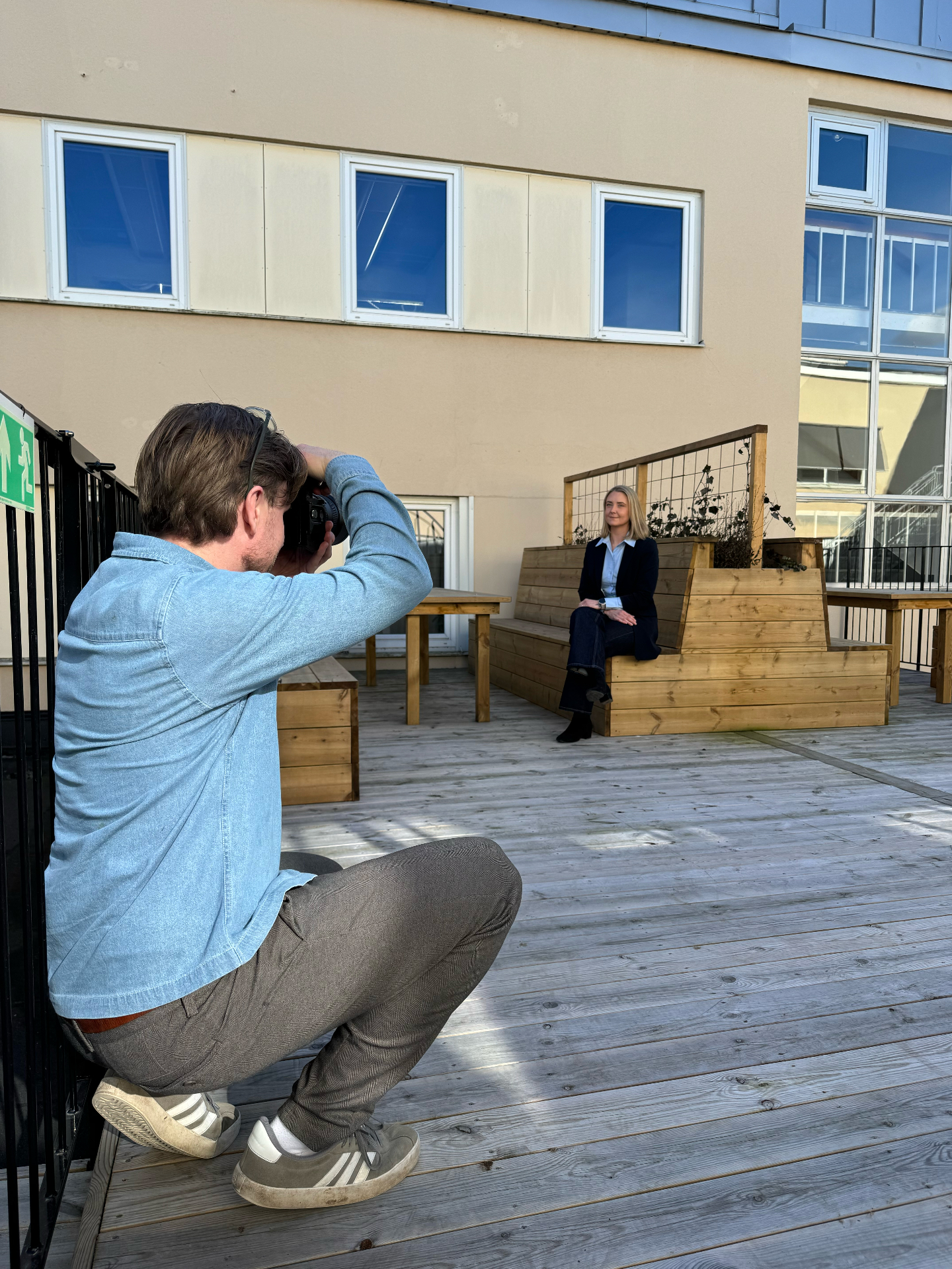 Daniel Alloh fotograferar porträtt utomhus på takterrass i kvällsljus.