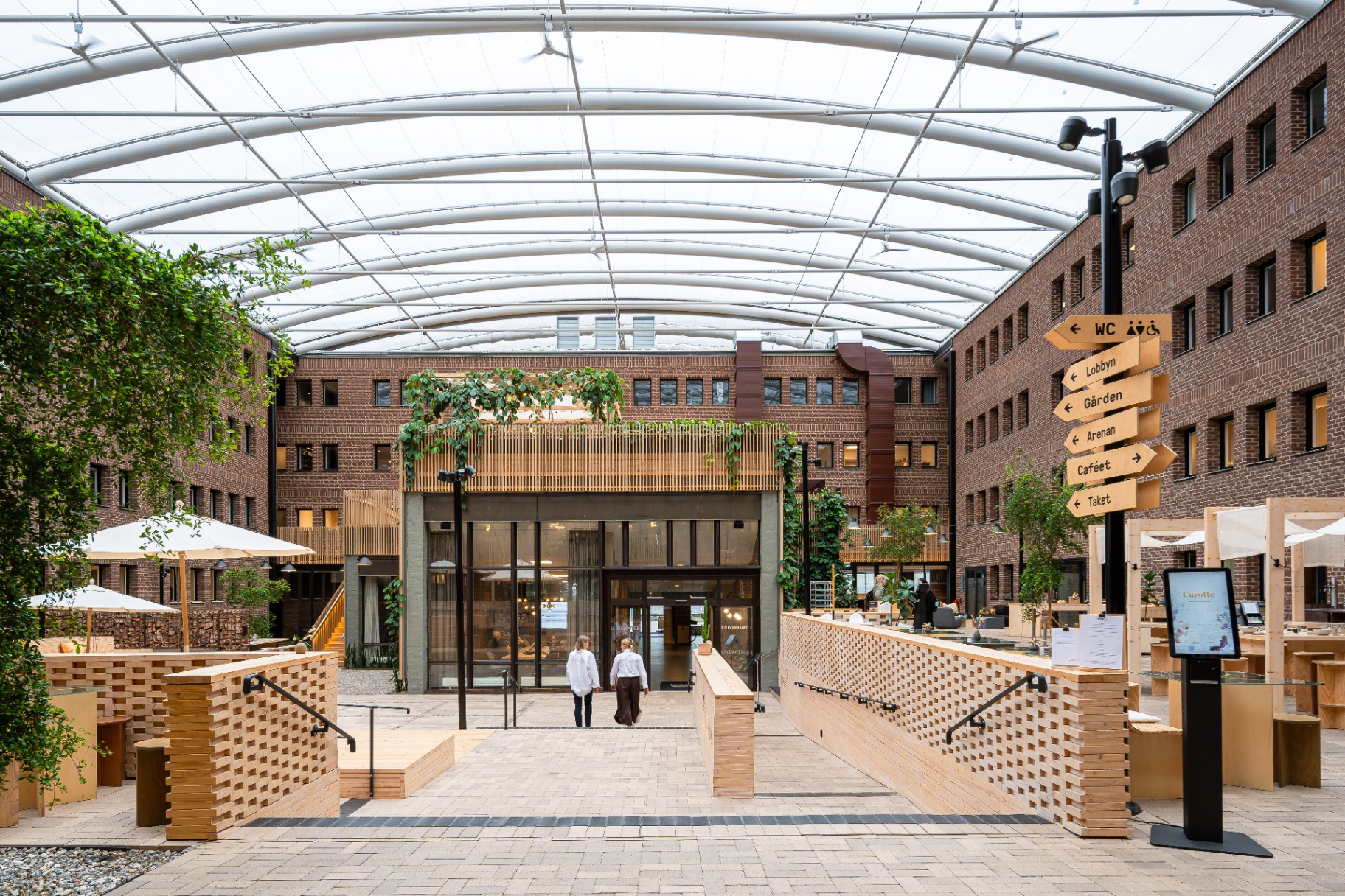Werket Jönköping – entré och innergård under det välvda glastaket, med skyltning till lobby, gård och café.