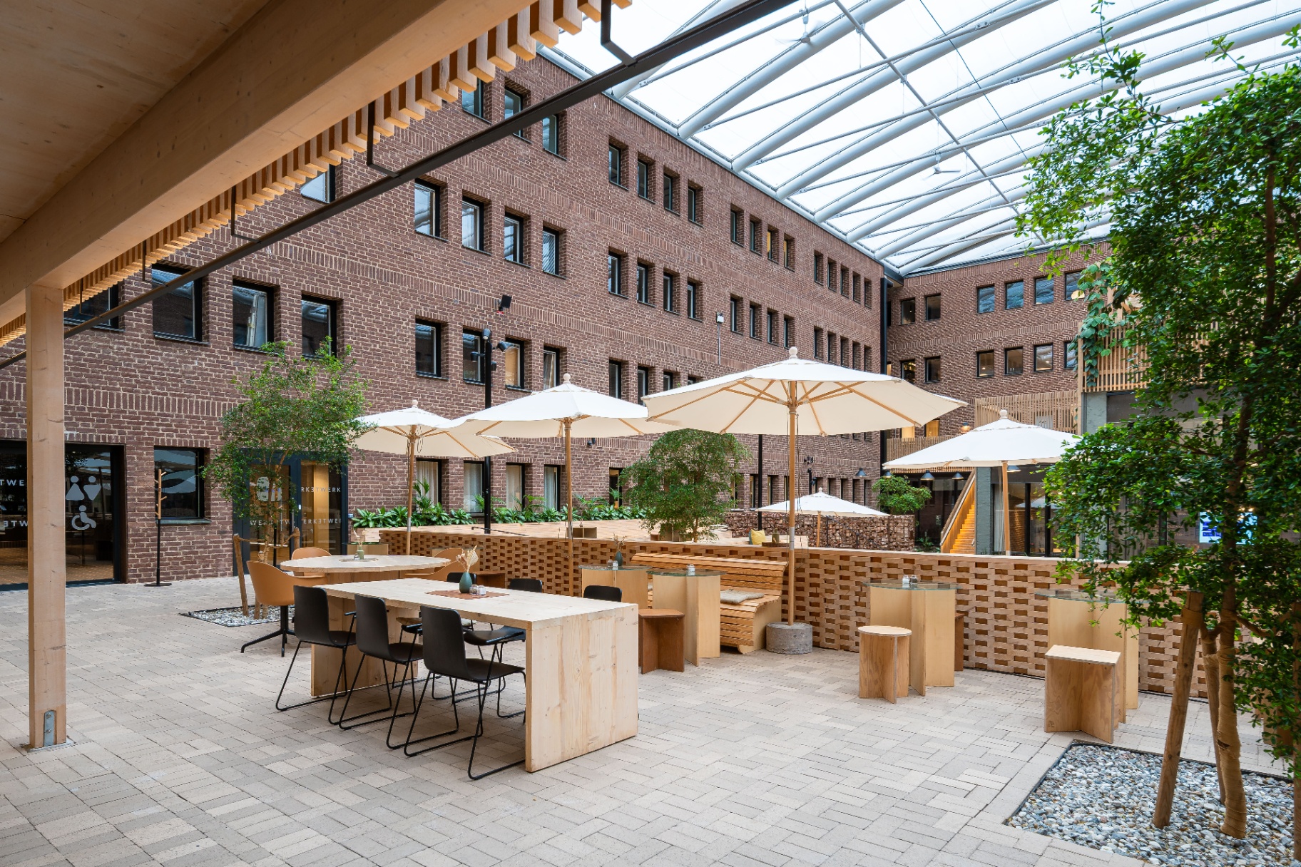 Werket Jönköping – cafémiljö med långbord, parasoller och tegelmur på innergården.