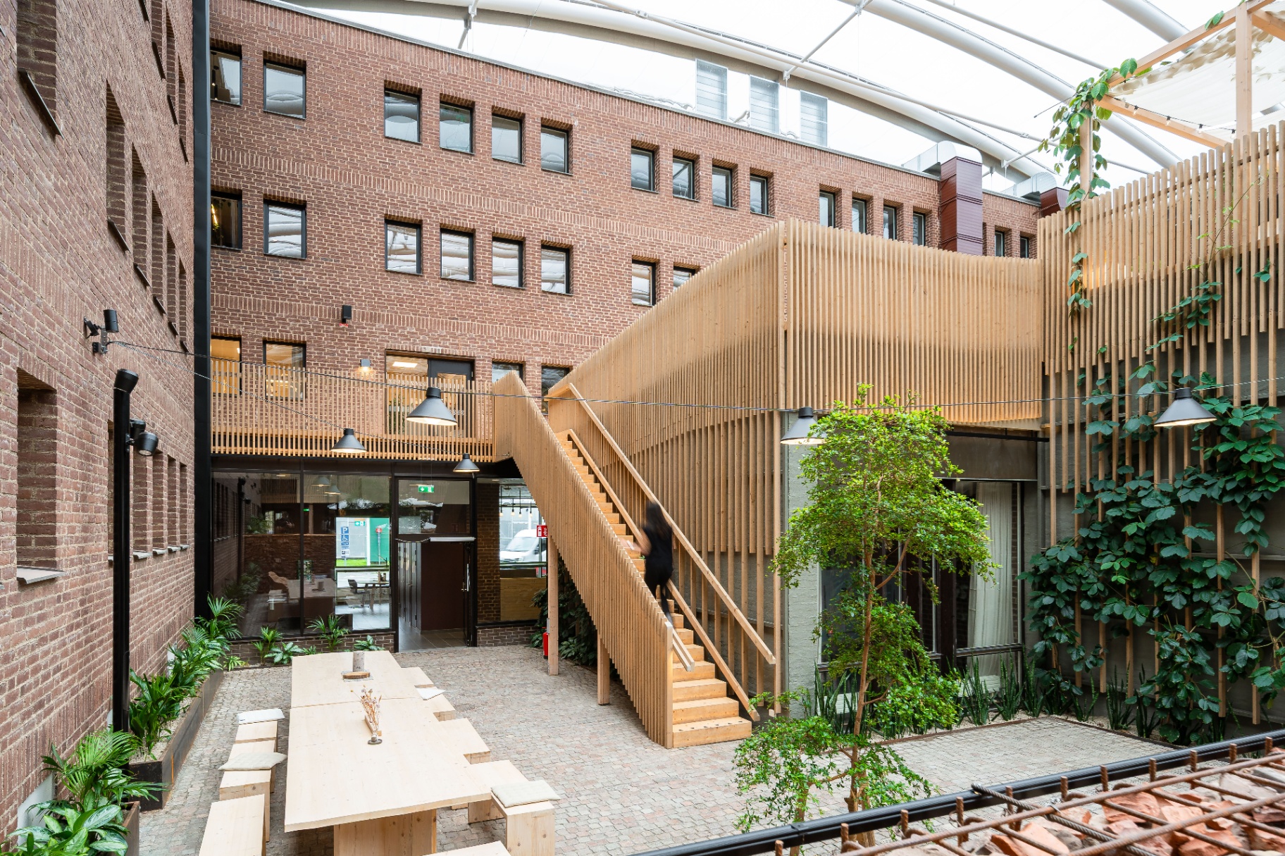 Werket Jönköping – översiktsvy av innergården med trätrappor, bord och grönska.