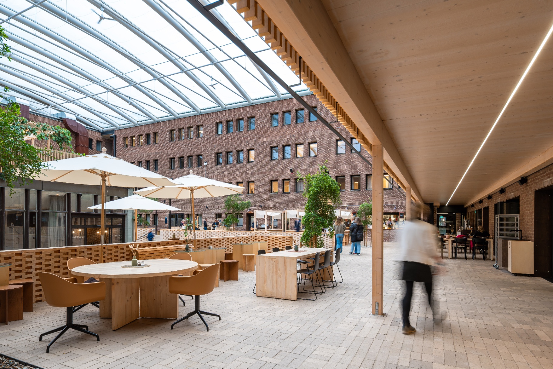 Werket Jönköping – öppen samlingsyta med träbord, parasoller och tegelfasader.
