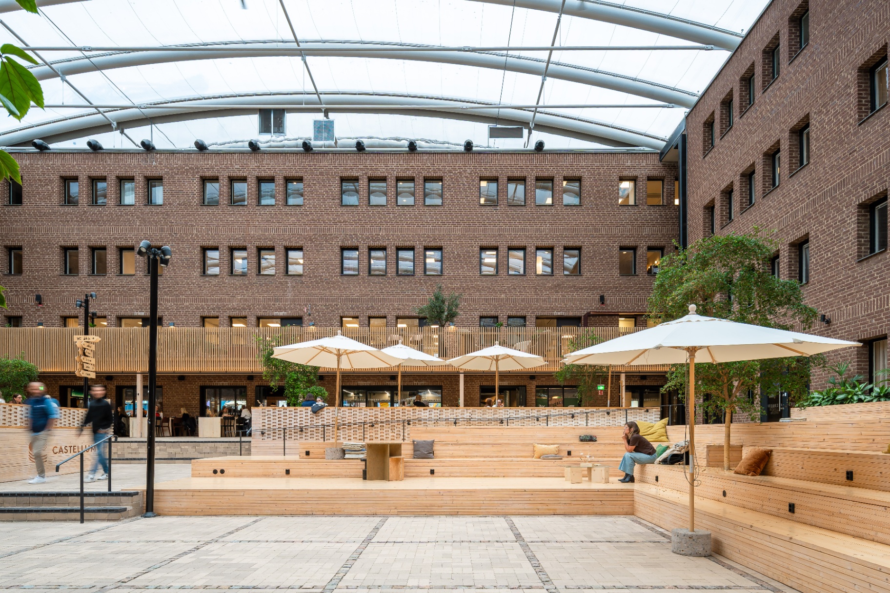 Werket Jönköping – läktare i trä framför restaurangzon och tegelfasad.